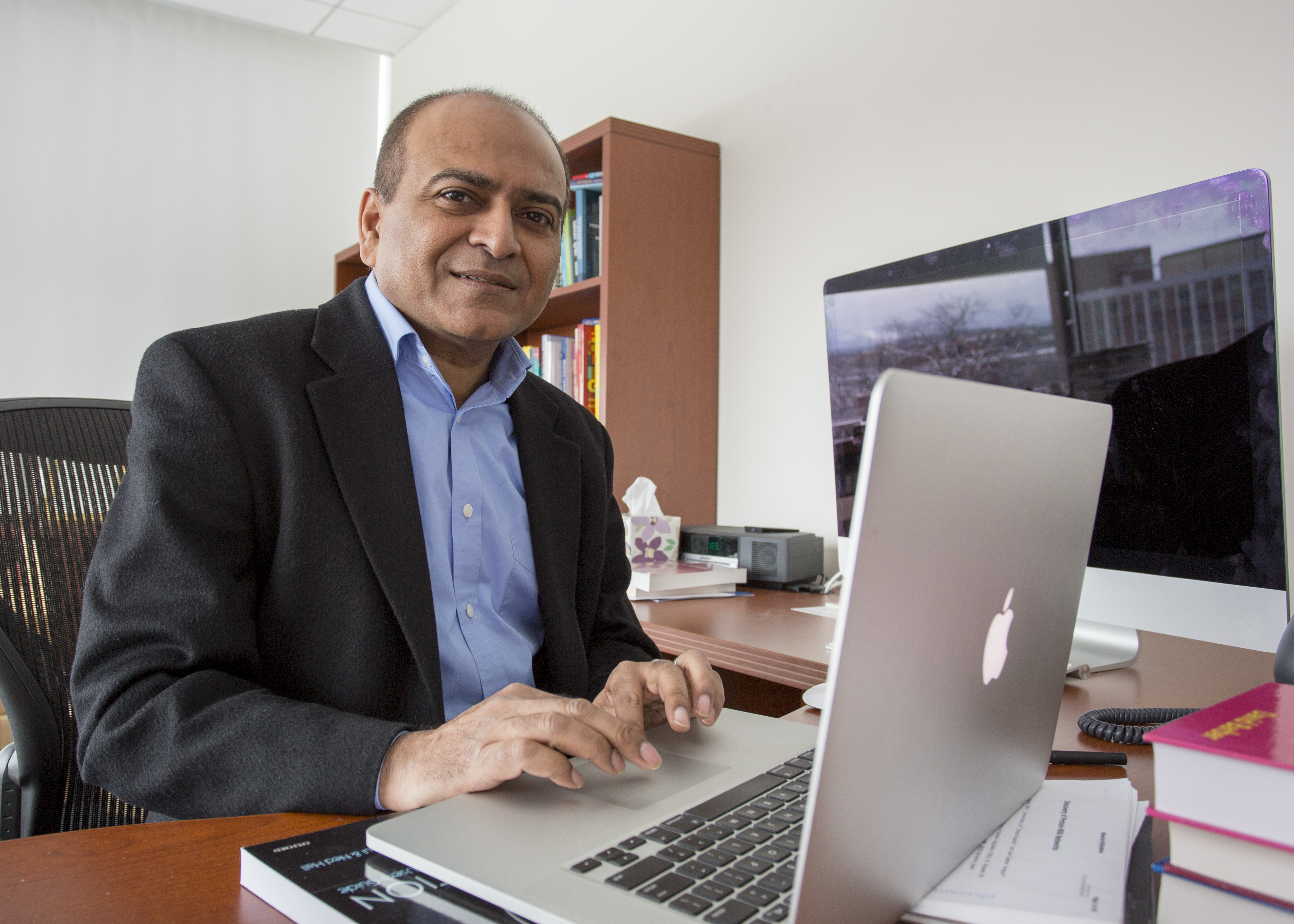 person in business attire seated at desk with laptop