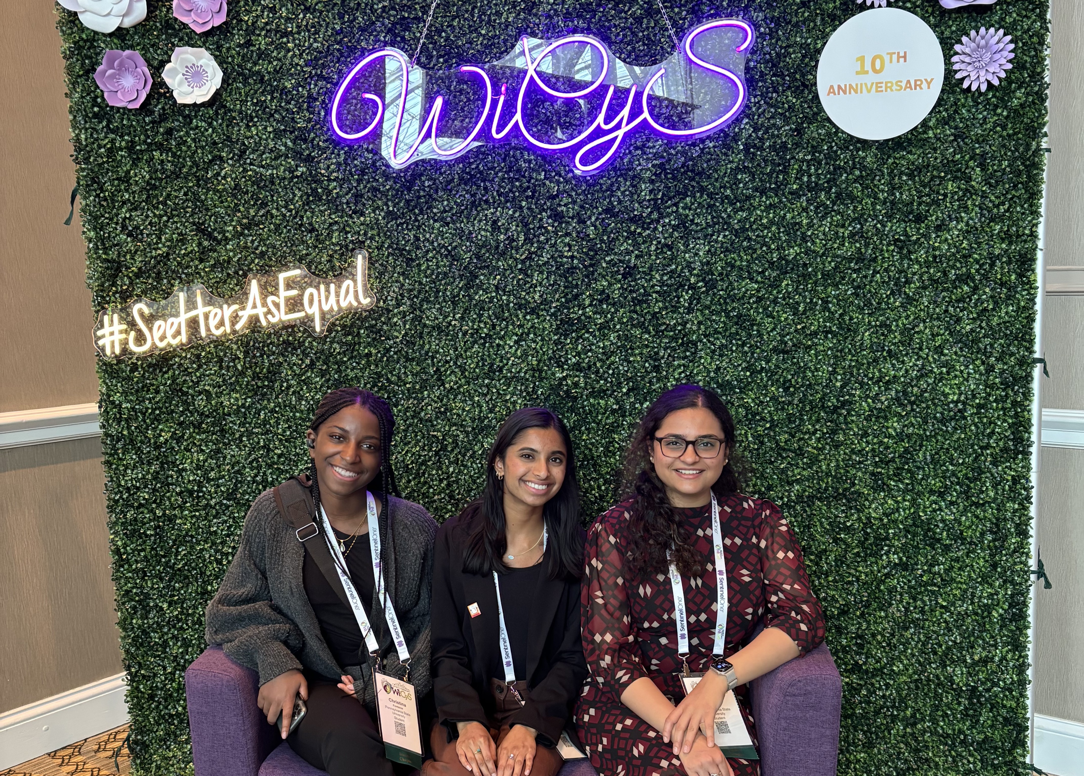 three people seated in front of colorful photo backdrop